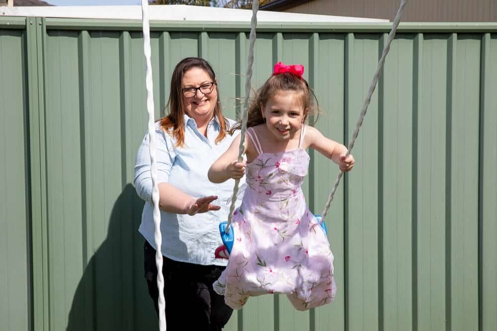 A single mother pushing her happy daughter on a swing